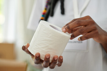 Hands of volunteer holding toilet paper donated for people in need