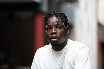 Portrait of young African American male showing short black hair braided hairstyle in the city outdoor - obrazy, fototapety, plakaty