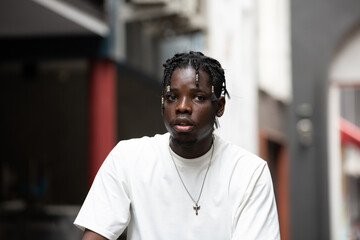 Fototapeta premium Portrait of young African American male showing short black hair braided hairstyle in the city outdoor
