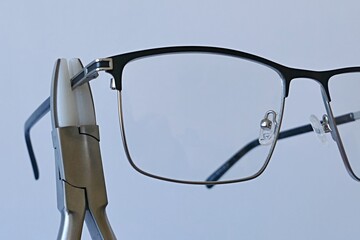 Adjusting temples on metal eyeglass frame with holding pliers equipped with replaceable nylon jaws...