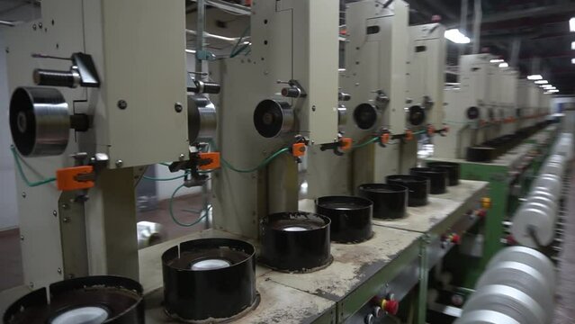 Yarn sools in a taxtile factory, small group of yarn spools in a textile mill close up, group of automated machines for yarn manufacturing, close up