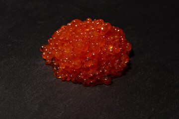 Red trout caviar on a black background.
