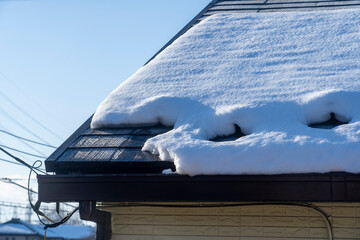 青空と太陽に照らされて解け始めた屋根の雪