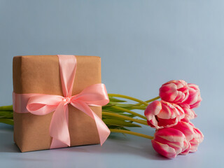 Spring flowers banner Pink tulips with a gift with a pink satin bow on a blue background. International women's day background
