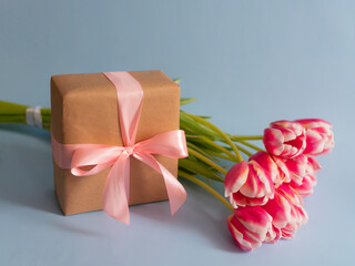 Spring flowers banner Pink tulips with a gift with a pink satin bow on a blue background. International women's day background