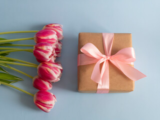 Spring flowers banner Pink tulips with a gift with a pink satin bow on a blue background. International women's day background