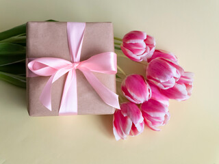 Spring flowers banner Pink tulips with a gift with a pink satin bow on a yellow background. International women's day background