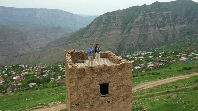 Travellers standing on top of ancient tower in Goor village with panoramic view of mountains valley