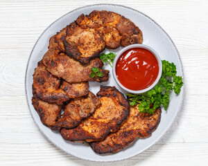 fried juicy pork steaks with ketchup on plate