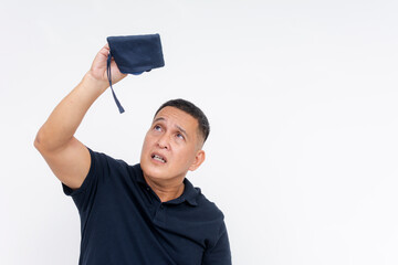 Middle aged Asian man with an expression of worry, looking into his empty coin purse, isolated on a white background, depicting financial distress.