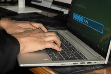 Hands typing on a laptop with a progress bar on the screen indicating 40% completion.