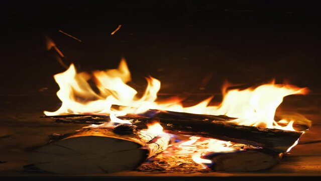 Vertical video, fire burning in the fireplace late in the evening, natural light from a fire, 4k video, background or screensaver idea about home comfort, footage from a static camera