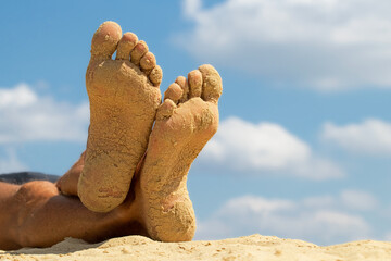 Male tanned feet in the sand.Man carefree resting on the beach.Concept of summer beach...