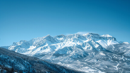 Fototapeta premium Clear blue skies reveal the stark beauty of rugged mountain peaks covered in pristine snow on a bright winter day.