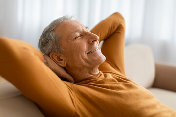 Closeup of happy joyful elderly man reclining on couch at home