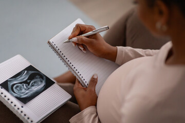 High angle view of black pregnant woman taking notes