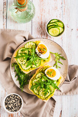 Bruschetta with guacomole, cucumber, egg and arugula on a plate top and vertical view