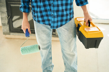Man hands holding paint roller and tool box