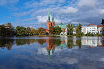 Lubeck, Germany. View of Lubeck Cathedral from the opposite shore of Muhlenteich (Mill pond) in autumn day. The cathedral was started in 1173 and consecrated in 1247. - 739339249