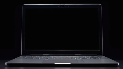 Open laptop with black screen against black background