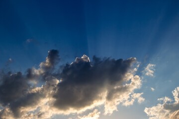 Sun rays on a background of blue sky and clouds during sunset