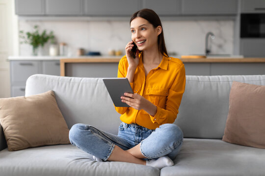 Young Woman Multitasking Using Tablet And Talking On Phone At Home