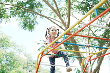 Fototapeta premium Little asian girl scrambles up the stairs in the playground. Background. Copy space. Learning Concept.