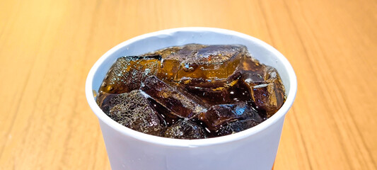 Soft drink in a white glass on a wooden table