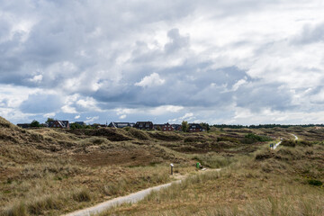 Spaziergänger in der Dünenlandschaft der Norseeinsel Amrum mit dramatischen Wolken - 739361691