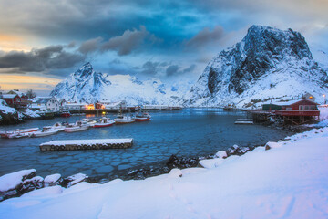 Winter landscape of picturesque harbor with fishing boat and traditional Norwegian rorbus in...