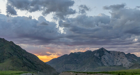 Fototapeta na wymiar rocky mountains under dark sunset clouds