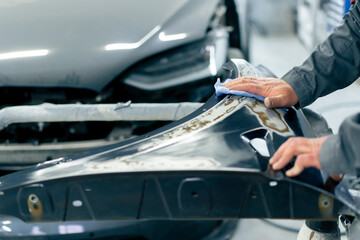 close-up at a service station an auto mechanic wipes a part of a blue car with a polishing rag