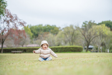 Fototapeta premium 屋外の自然あふれる公園内で楽しそうに笑顔ではしゃぐ1歳の幼児