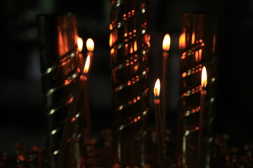Fire of memory. Turning to God. Silent prayer. A burning candles in the dark against the background...