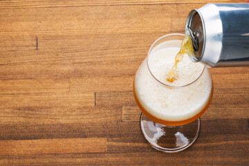 Pouring craft beer into pint glass on a wooden table - obrazy, fototapety, plakaty