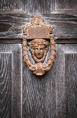 An old decorative door knocker on a strong timber door