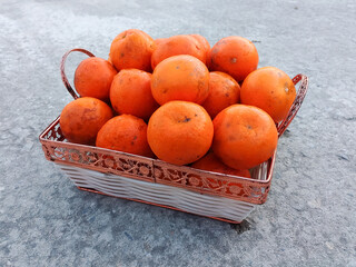 A wicker basket full of fresh orange fruits on the floor
