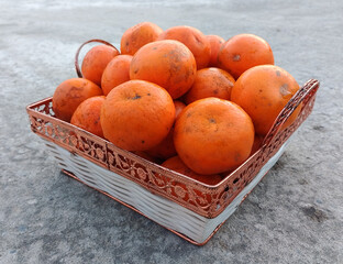 A wicker basket full of fresh orange fruits on the floor