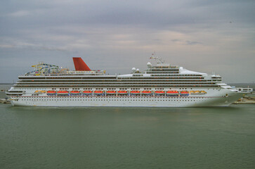 Huge cruiseship or cruise ship liner in port at terminal with skyline and shore view under blue sky...