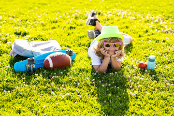 Happy child enjoying on grass field and dreaming. Summer holiday. Healthy lifestyle concept.