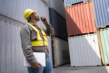 Middle east logistic worker foreman use walkie talkie and computer notebook working at container site	