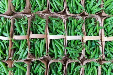 Fresh green peas in the store. View from above. Green pea pods in a basket on a store counter.