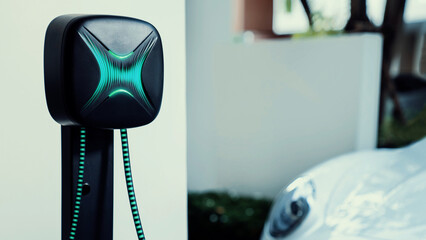 Electric car plugged in with home charging station to recharge battery by EV charger cable. Future...