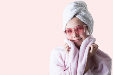 Pleasant girl with towel on her head isolated on a pink background. Skin care concept. spa treatments, cosmetology, makeup.