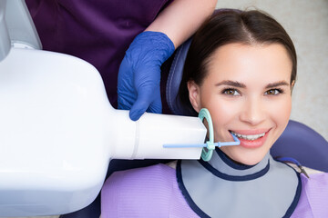 A dental assistant readies a patient for an X-ray procedure using specialized tools in the clinic