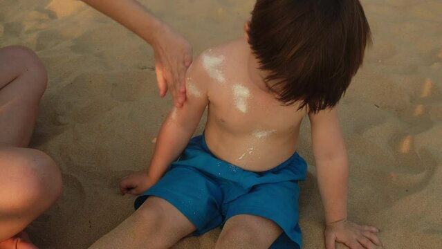 Protecting skin from sunburn. Mom applying sunblock to toddler son. 