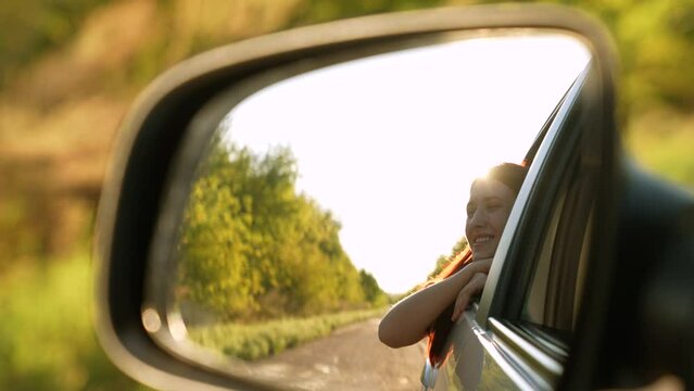 Smiling travel woman looking at window car road trip enjoy summer trees sun light back mirror reflection view. Happy female tourist admiring scenery freedom explore lifestyle adventure auto driving