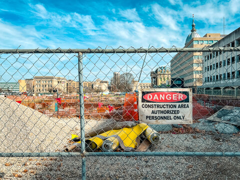 Looking through a fence to a major construction site at the Illinois State Capitol Complex. Sign reads, "Danger Construction Area Authorized Personnel Only". 