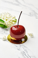 Tempting cherry-shaped pastry with white flowers on marble