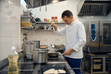 Man in uniform prepares food in a restaurant kitchen